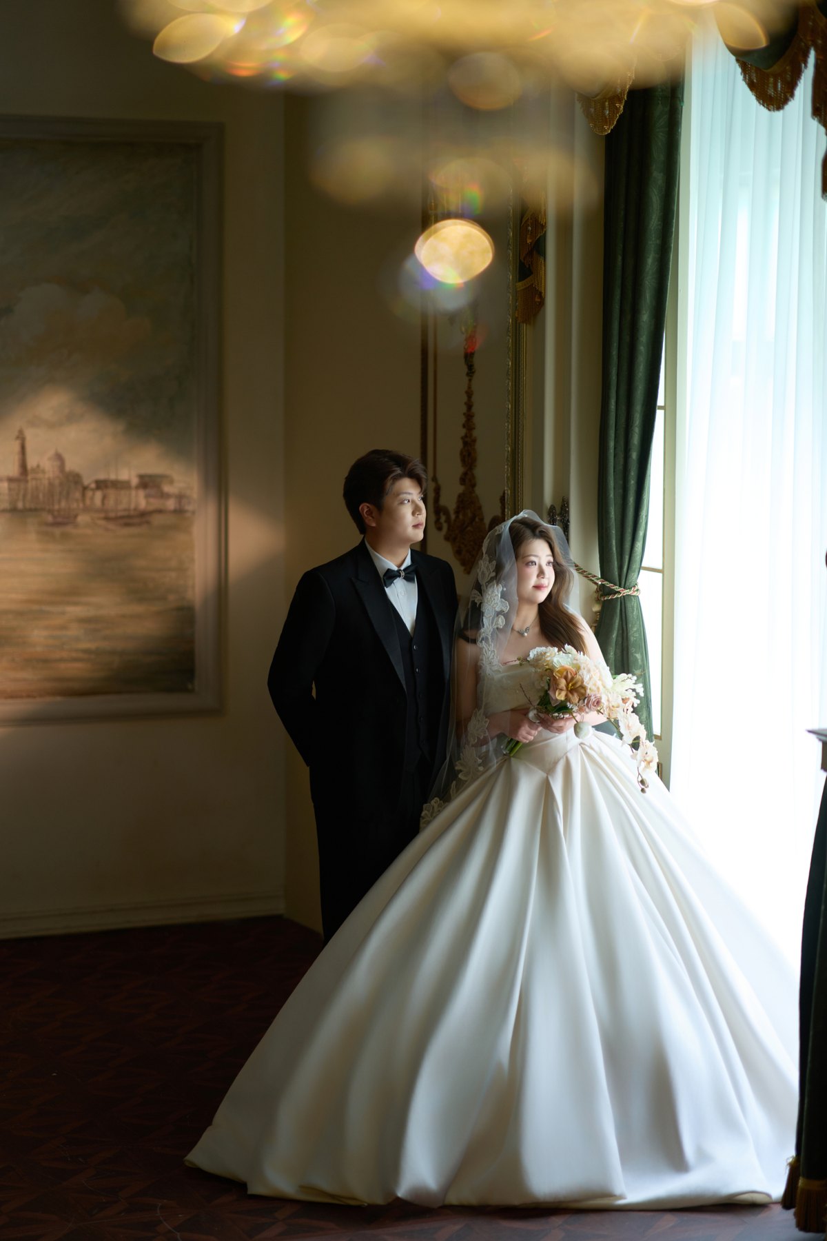 新人依偎在窗边,暖光映照婚纱